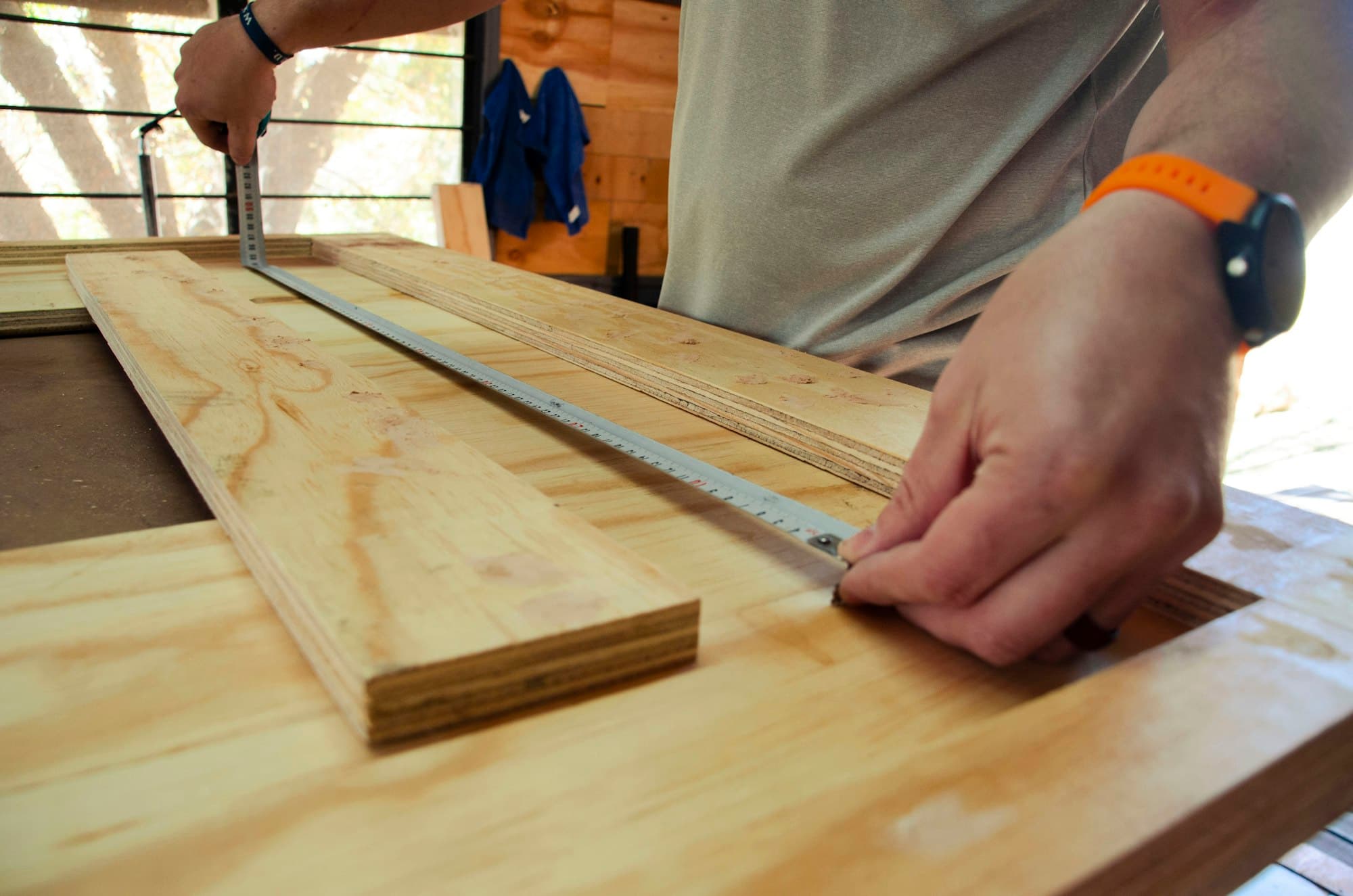 Hände messen ein Holzbrett mit dem Maßband an